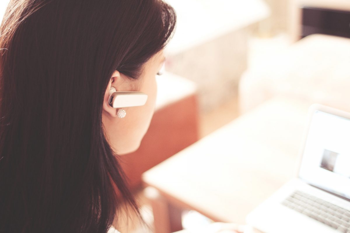 Woman on a laptop with an ear piece in