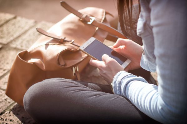 Social Media eCommerce Someone sat down outside using their mobile device.